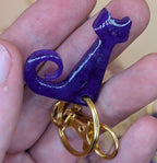 Purple keychain held in a hand with a blurred background