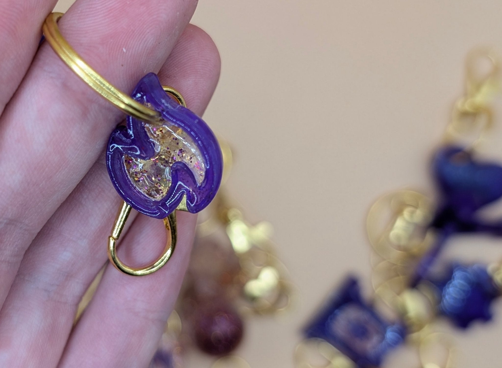 Purple and gold decorative item held in a hand with a blurred background