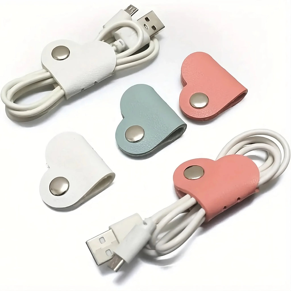 Heart-shaped cable organizers in white, pink, and blue on a white background