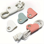 Heart-shaped cable organizers in white, pink, and blue on a white background