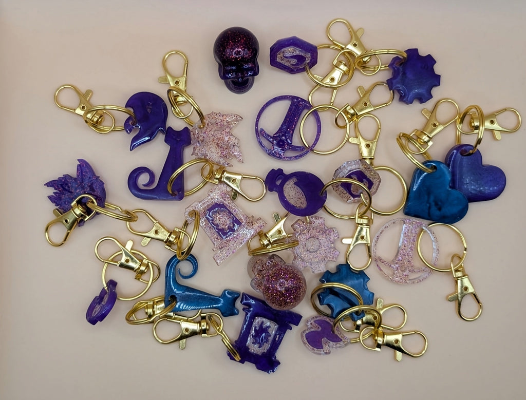 Collection of colorful keychains with various shapes and designs on a beige background